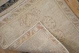 Curled edge of vintage distressed Oushak rug, showing machine-bound side and worn pile.