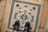 Vintage Oushak square mat in beige and blue shown to scale, highlighting its worn texture.
