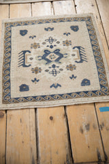 Angled view of a distressed Oushak mat showing its navy medallion and wave border.