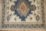 Distressed Oushak rug with dusty denim blue gul, germinating finials, and ivory vine border.