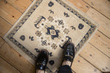 A vintage distressed Oushak mat on wood flooring, styled with loafers to show scale.