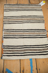 Close-up of vintage Turkish kilim rug's ivory, black, beige banded lines and polychromatic selvage.