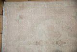 Distressed Oushak rug texture with mostly even wear, faint foundation, and machine-bound edge.