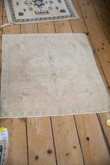 Detail of the distressed vintage Oushak rug, showing its soft ivory pile and faint floral patterns.