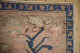 Distressed Oushak corner: dusty rose field, oversized blossom, sapphire blue palmette border.