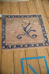 Distressed Oushak rug corner; dusty sapphire blossom, dusty rose field, palmette border, magenta flecks.
