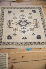 Distressed Oushak rug detail, ivory field with dusty navy geometric motifs and wave border.