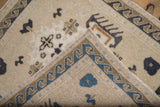 Folded distressed Oushak rug revealing machine bound edge and reciprocating wave border.