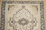 Serrated medallion, dusty royal blue, and pale coffee brown meandering vine border on a distressed Oushak rug.