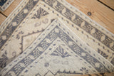 Tightly woven foundation, machine-bound edge, and worn geometric pile of the Oushak rug.