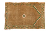 Vintage Distressed Oushak rug in ochre with emerald green stepped spandrel and central floral.