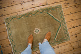 Distressed ochre Oushak rug corner with emerald green zigzag border and stepped spandrel.