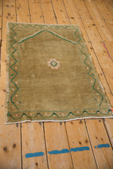 Distressed vintage Oushak rug corner with ochre pile, emerald green vine border.