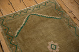 Distressed ochre field texture of vintage Oushak rug with pink floral detail.
