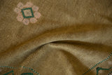 Distressed ochre pile texture featuring partial pink and emerald green floral motif.