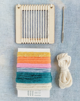 Detailed view of Lil Loom Weaving Kit components, with colorful yarns and a 3 inch wooden loom.