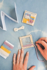 Lil Loom Weaving Kit with hands weaving soft bright yarns on a 3x3 wooden loom.