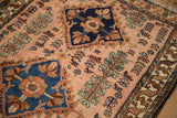 Finely knotted botanical motifs in sapphire blue and copper on a lustrous dusty rose field.