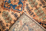 Corner of a vintage Mehriban rug showing the hand-knotted back and glossy rose-colored pile.