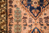 Detailed view of stylized shrubs and plants on the dusty rose field of a collector rug.