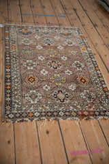 Mauve ground and geometric floral patterns on the antique Caucasian rug's tattered corner.