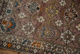 Antique Caucasian rug: geometric border, serrated panels, floral blossoms, mauve and tangerine abrash.