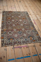 Tattered edge details of an antique Caucasian rug showing geometric ivory and mauve patterns.