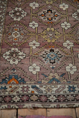 Antique Caucasian rug's lower border, mauve field with geometric vines and ivory florals.
