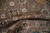 Curled detail of Antique Caucasian rug, showing abrashed mauve ground and geometric floral patterns.