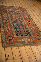 Side profile of an antique Kurdish Hamadan rug, showcasing its terracotta Samovar border and geometric navy field.