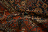 Folded view of an antique Kurdish rug showing rich texture and geometric motifs in terracotta and navy blue.