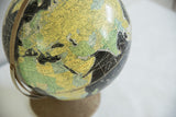1960s Rand McNally black globe with yellow-green landmasses of Europe and Asia.