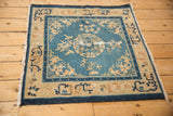 Full angled view of the antique Peking square rug showing its complete design and characterful wear.