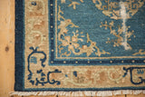 Corner of an antique Peking rug with arabesque and seed pearl borders next to ivory fringe.