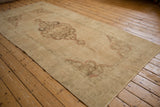 Vintage Oushak rug runner detail: distressed scalloped medallion, muted beige field, faded red outlines.