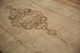 Distressed vintage Oushak rug detail: scalloped medallion in beige, dusty brown, and cinnabar tones, low pile.