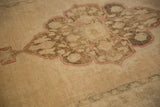 Distressed Oushak rug detail: scalloped medallion with floral fills and dusty cinnabar outline.