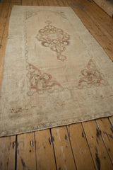 Distressed vintage Oushak rug runner corner with faded beige pile and machine finished edge.