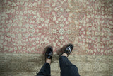 Distressed vintage Sparta rug with dusty rose thousand flower field meeting arabesque border.