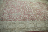 Abrashed dusty rose field with faint foundation wear and arabesque border.