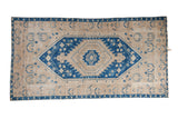 A vintage distressed Oushak runner with a concentric sapphire blue medallion on a sand-colored, geometric field.
