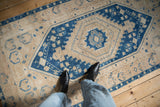Vintage distressed Oushak runner with a bold blue medallion styled on a wooden floor.