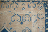 Low pile wear and blue geometric starburst motifs on a distressed vintage Oushak rug corner.