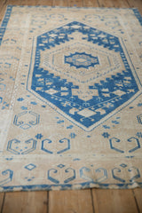 Angled view of a vintage Oushak runner's blue stepped medallion and distressed low-pile texture.