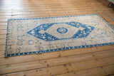 A vintage Turkish Oushak runner seen from an angle, showing its distressed texture and blue stepped medallion.