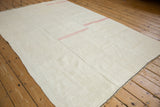 Angled view of a vintage hemp kilim highlighting its multi-panel construction and simple pink stripes.