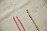 Vintage hemp kilim corner showing embossed numbers on the front and pink stripes on the hand-woven back.