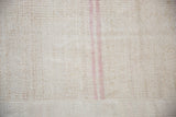 Close view of the seam and dusty mauve stripes on a textured vintage hemp kilim.