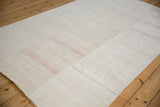 The seamed, paneled body of a handwoven hemp kilim with faint dusty pink and black horizontal stripes.