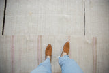 Detail of a vintage hemp kilim's seamed panels and textured flat weave with soft stripe accents.